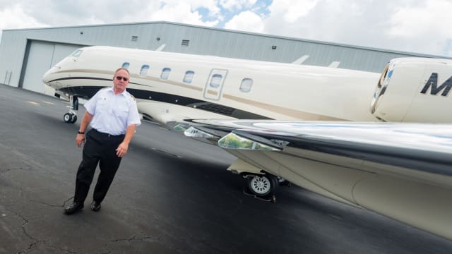 bariatric patient who is a pilot poses in uniform by plane